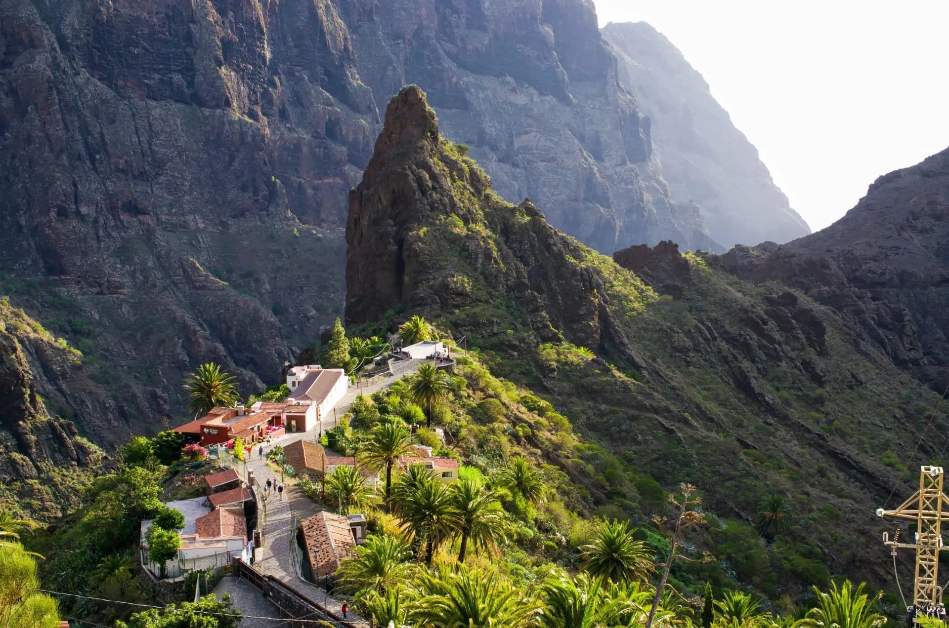 Mountains surround the village of Masca on Tenerife with lush green slopes and palm trees.