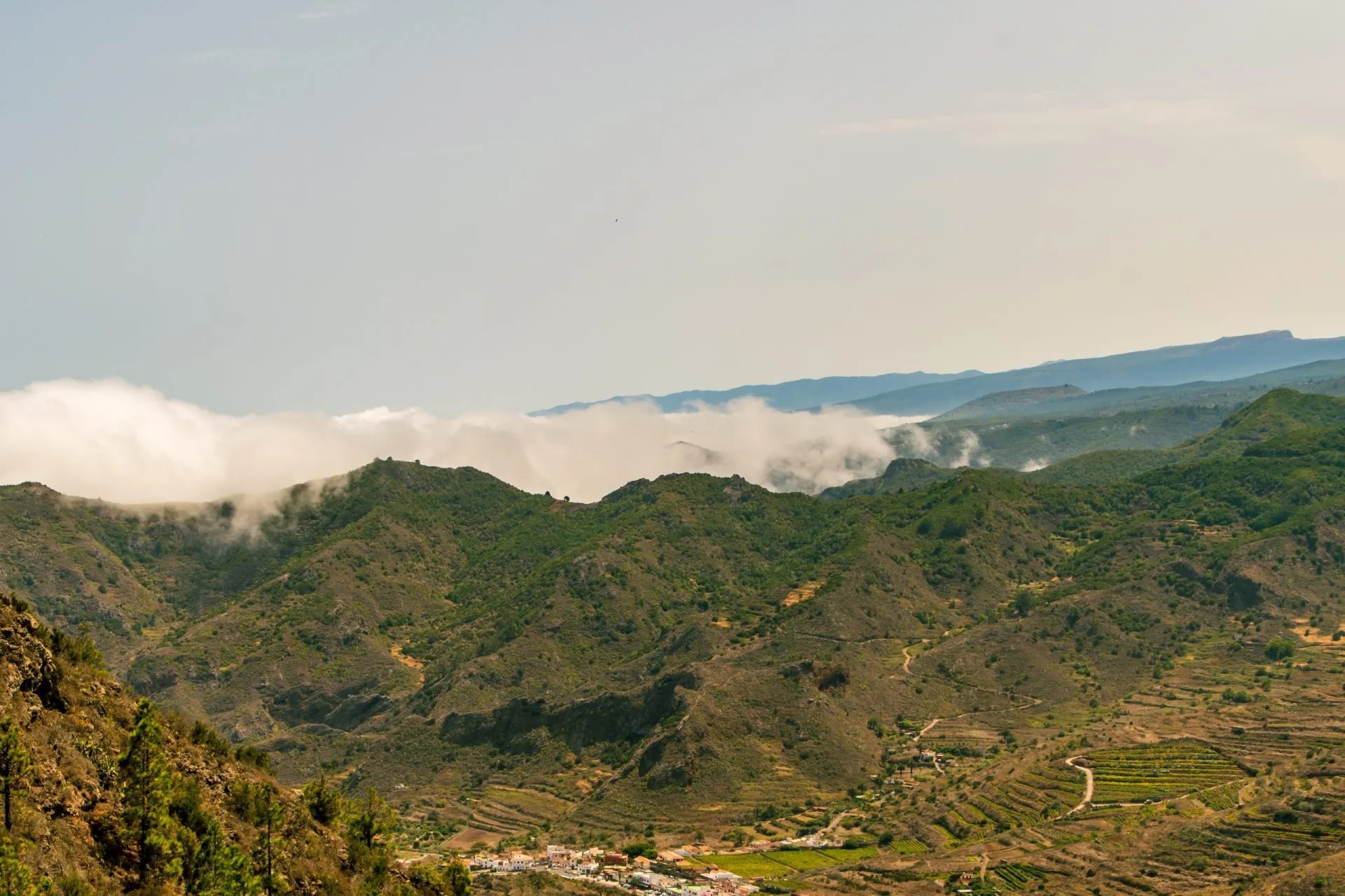 Green mountains in Teno Alto, Tenerife, with clouds hugging the peaks and a small village below.