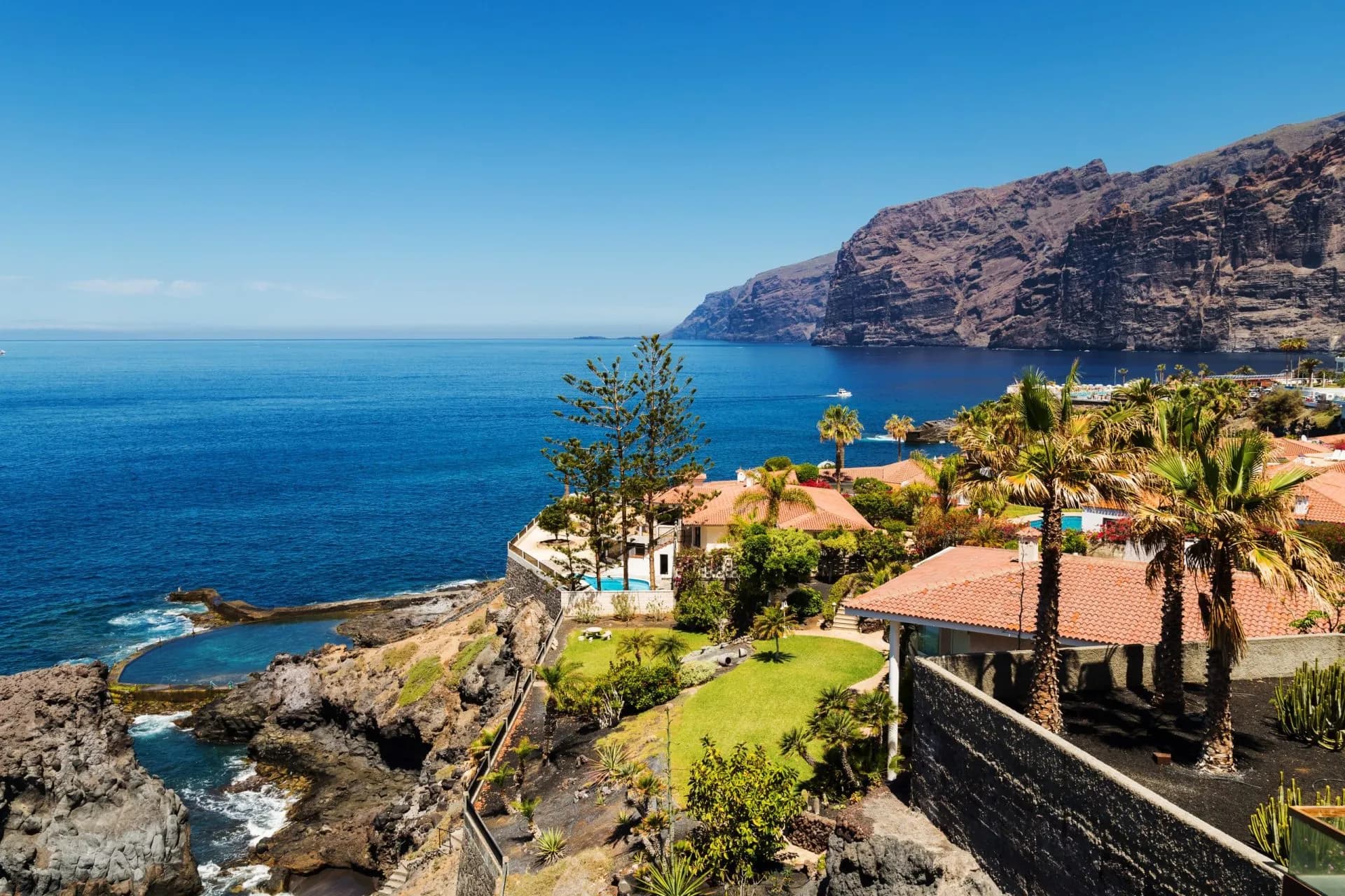Giant rock formations, Acantilados de los Gigantes, Los Gigantes, Tenerife coast with blue sea and villas.