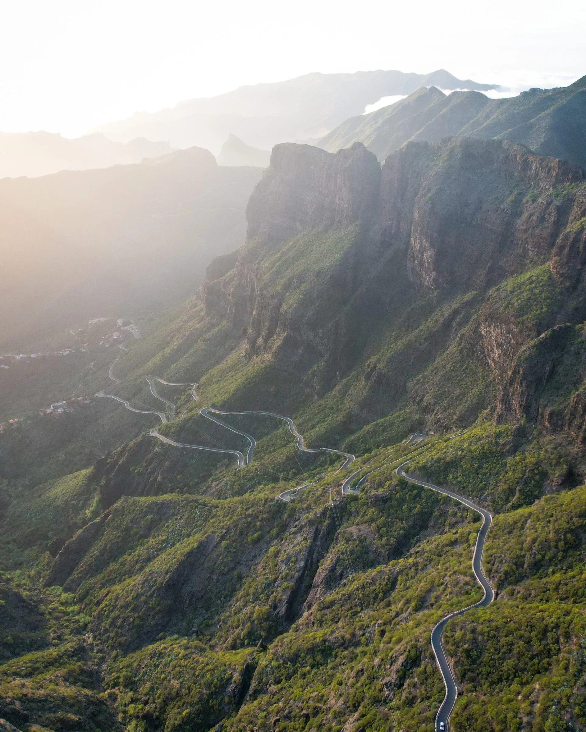 Winding mountain road with hairpin turns through lush green slopes in Masca Valley, Tenerife.